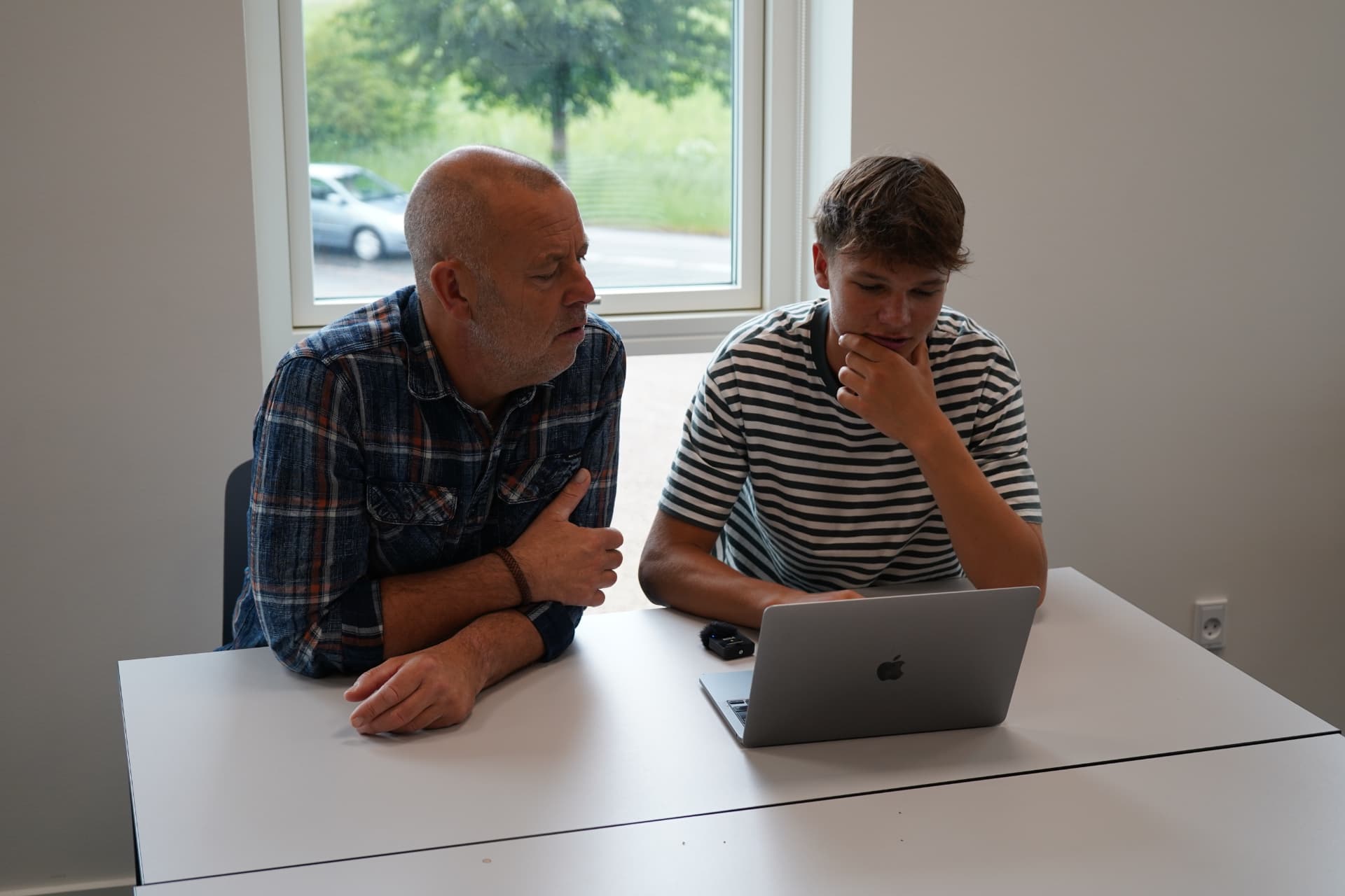 Elev i tankepause ved skrivebordet med sin lærer